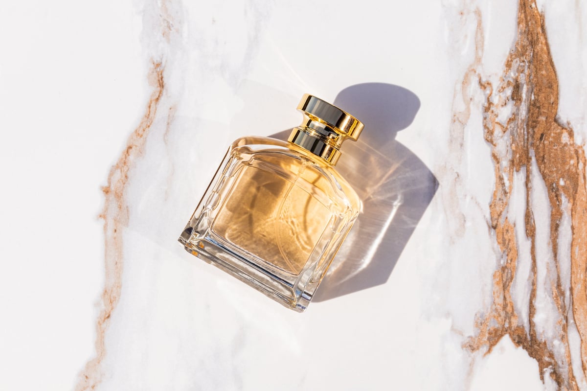 Perfume bottle with gold cap on abstract marble background
