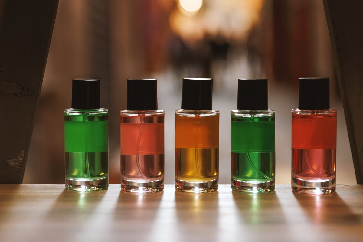 Five transparent glass spray bottles with colorful liquids